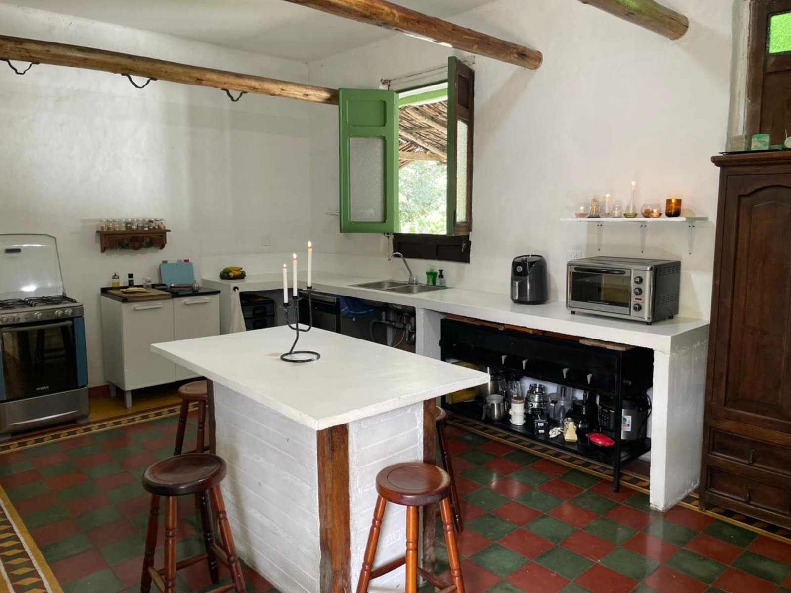 The rustic farmhouse kitchen with wood-beam ceiling and green tile floor